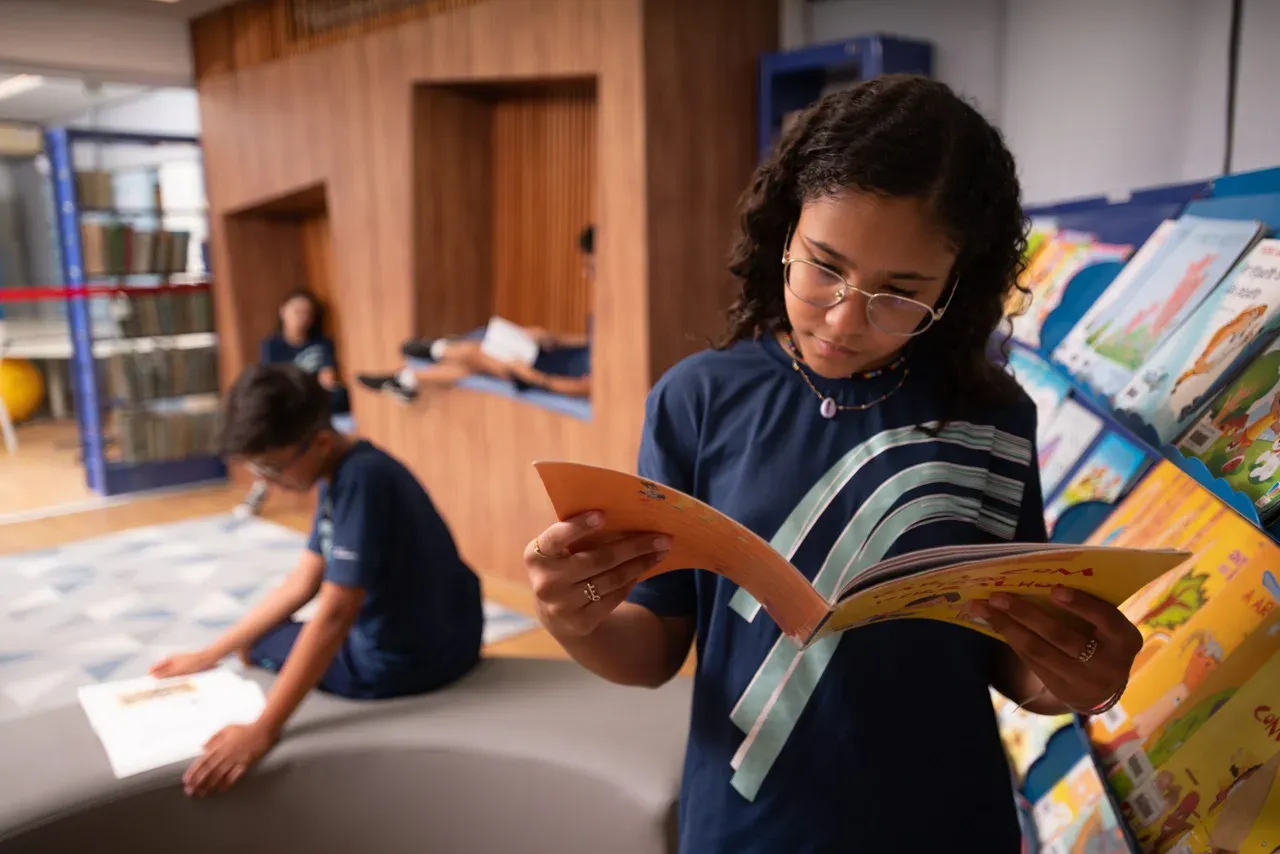 Estudante explorando livros e leituras na biblioteca da Escola Crescimento
