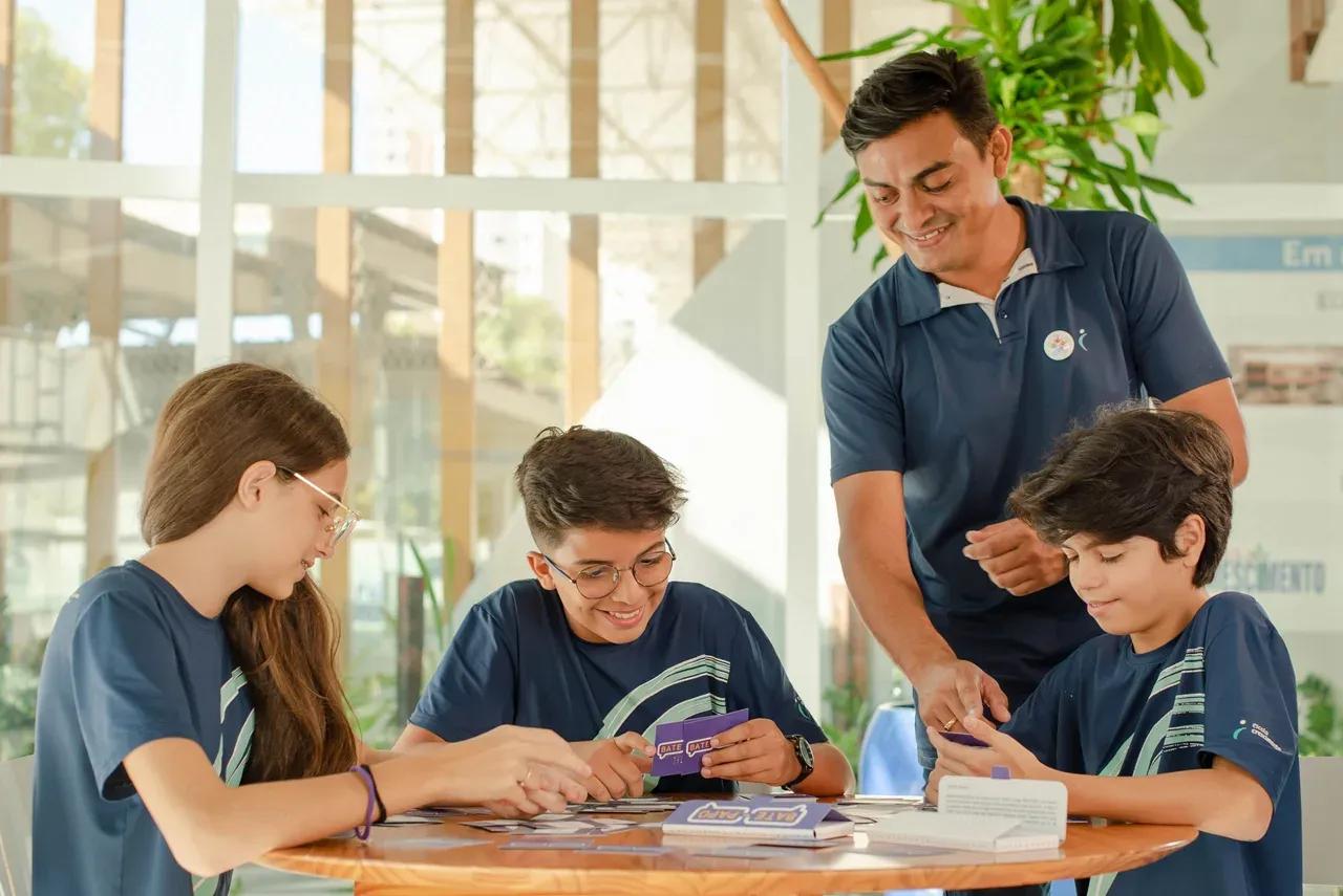 Professor acompanhando estudantes em uma atividade colaborativa na Escola Crescimento