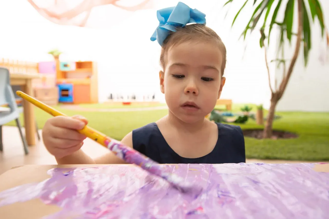 Criança explorando materiais artísticos em uma atividade pedagógica